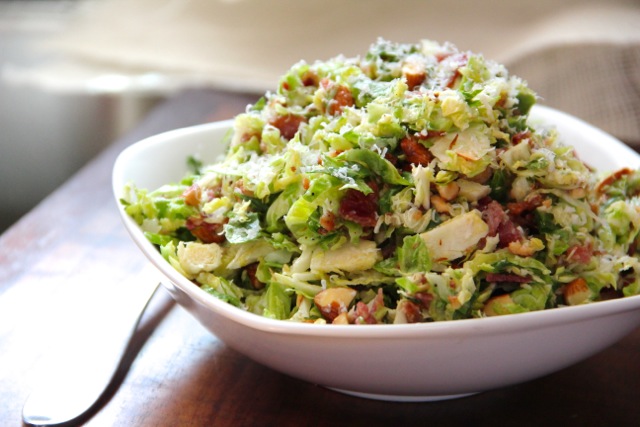 A crisp raw brussels sprout salad with bacon and almonds topped with a ...